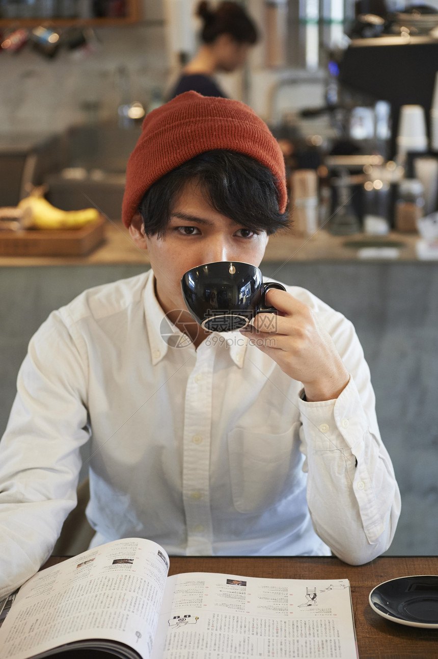 看着杂志喝咖啡的年轻男士图片