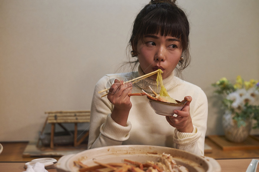 年轻女性开心的吃着螃蟹火锅图片
