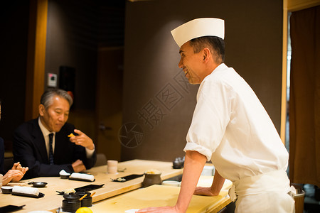 寿司店里的顾客和厨师背景图片