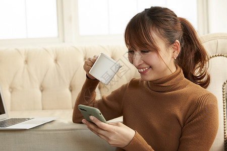 居家喝茶看手机的女人图片