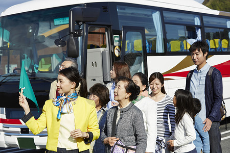 公交车导游拿着旗帜带领旅游团的年轻导游背景