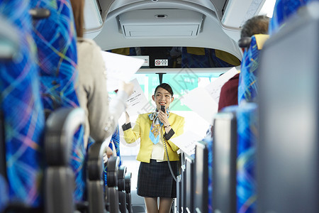 巴士上为旅客讲解旅行手册的导游图片