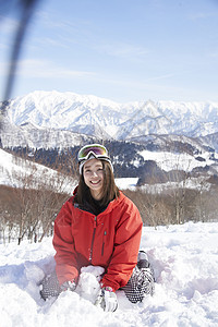  坐在雪地里开心玩雪的女性图片