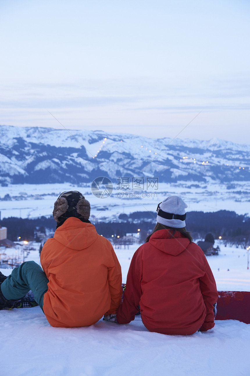 滑雪场地上并排而作的的情侣图片