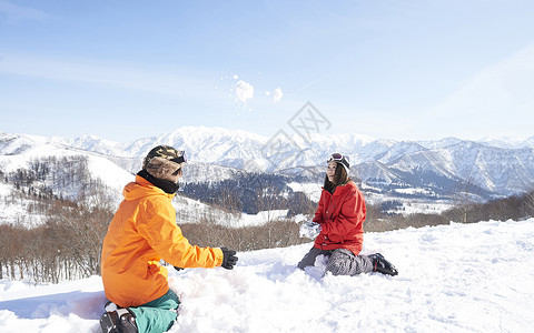 滑雪场地上打雪仗的情侣图片