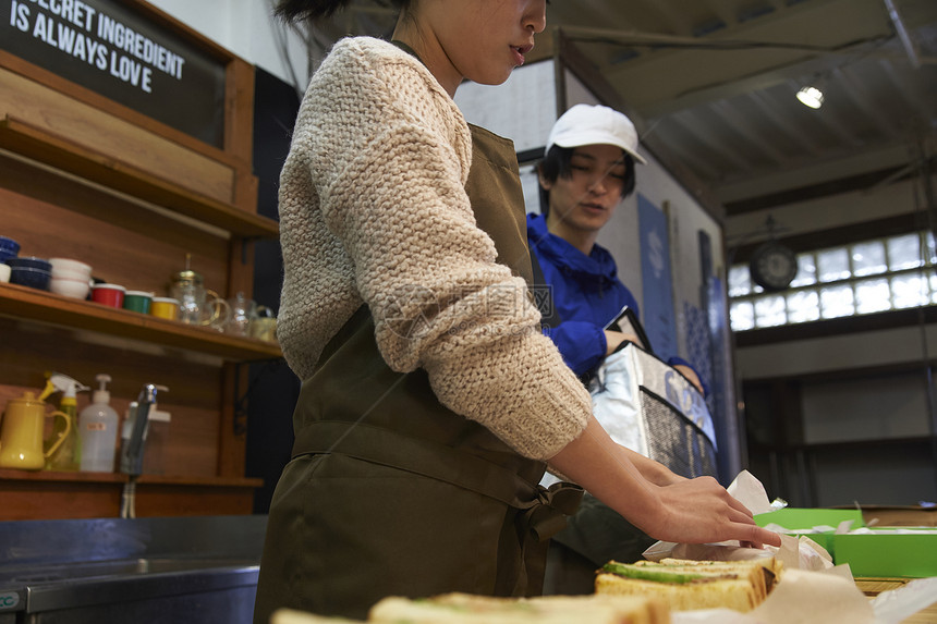 在等待餐厅服务员打包食物的外卖员图片