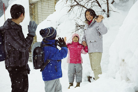 下雪天告别母亲背着书包上学的孩子们图片