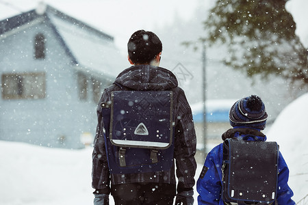 下雨天背着书包雪地里行走的学生背影图片