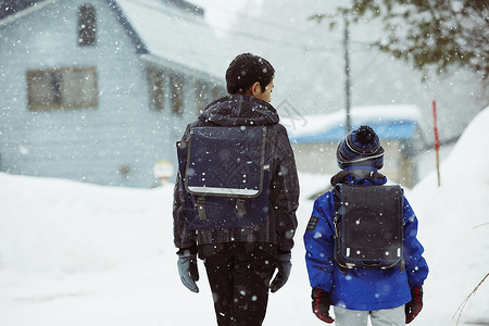 下雨天背着书包雪地里行走的学生背影图片