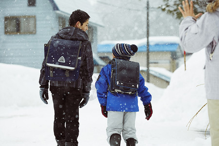 下雨天背着书包雪地里行走的学生背影图片