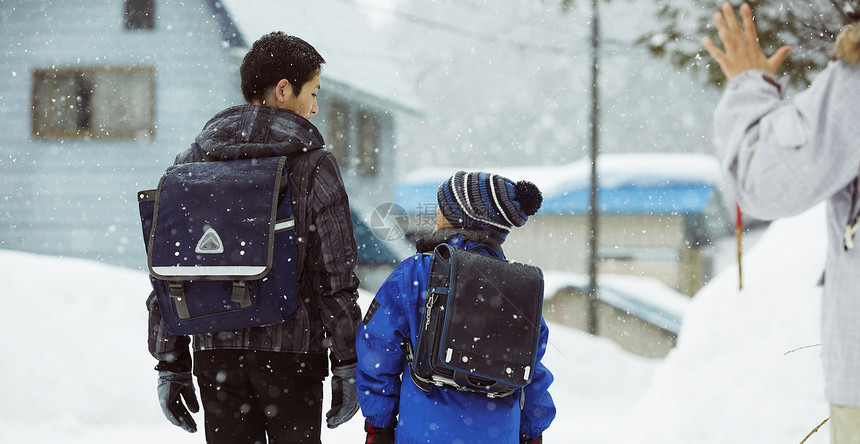 下雨天背着书包雪地里行走的学生背影图片