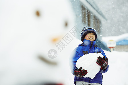 户外雪地抱着一大块雪的小男孩图片