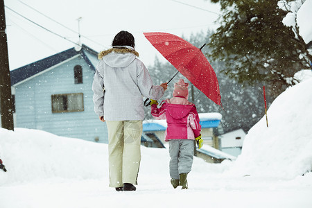 雪天撑着雨伞散步的母女背影图片