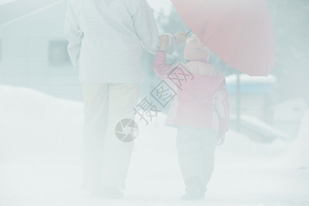 雪天撑着雨伞散步的母女图片