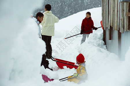 雪地里使用雪铲除雪的孩子们高清图片