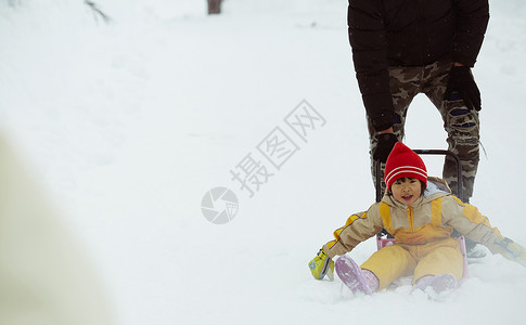 父亲推着小女孩的雪橇在雪地里玩耍图片