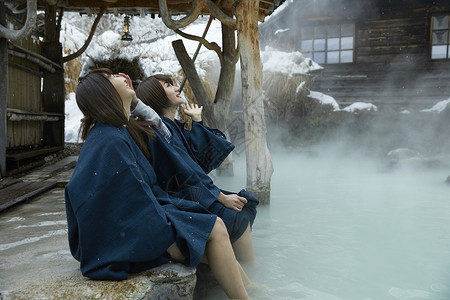 温泉区冬季雪天户外泡温泉的少女背景