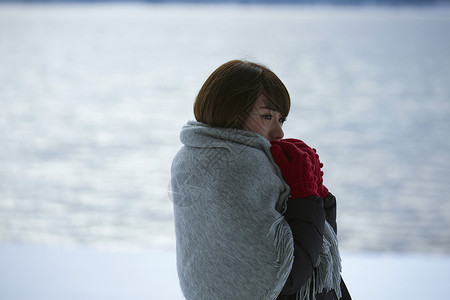 披着毯子的女性在寒冷冬天的雪地里图片