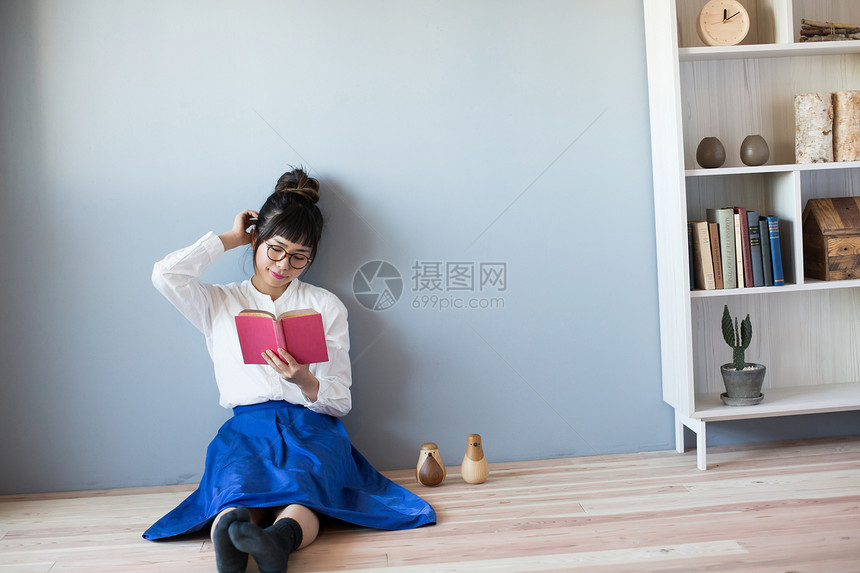 坐在地上阅读书籍的女性图片