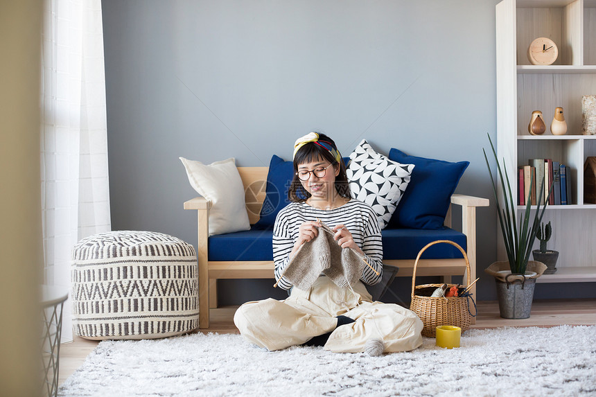 客厅地毯上编织毛线的少女图片