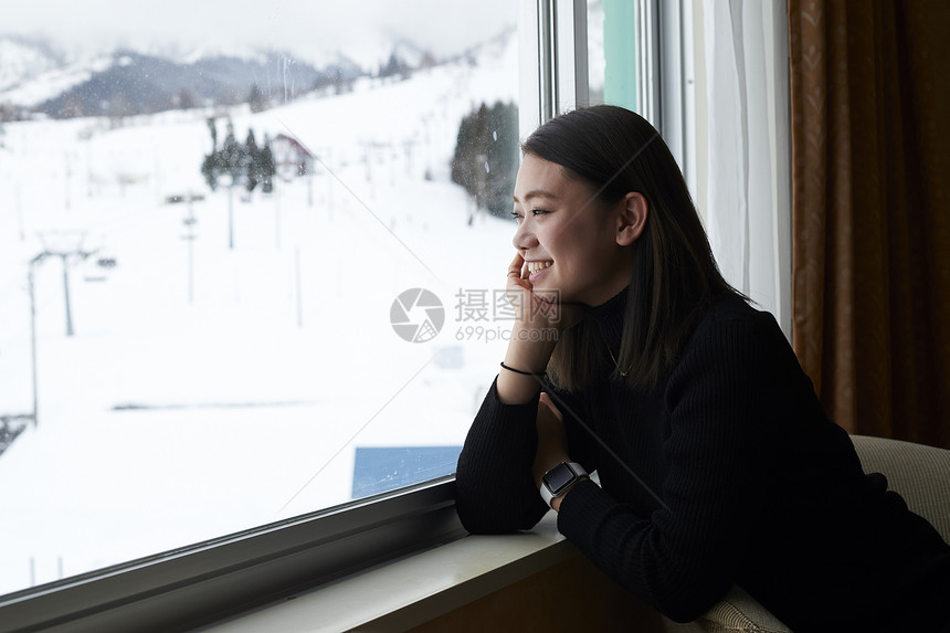 在窗边看雪景的女性图片