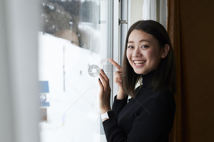 在窗边看雪景的女性图片