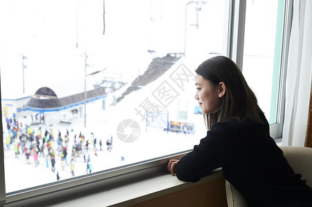 在窗边看雪景的女性背景图片