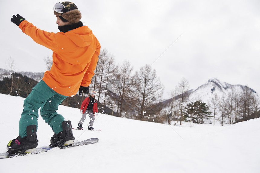 滑雪场展示高难度的单板男孩图片
