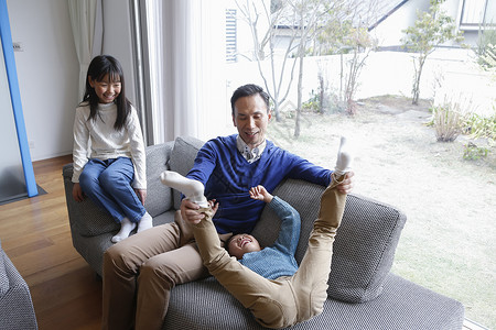 坐在客厅沙发上放松玩耍的孩子和父亲图片