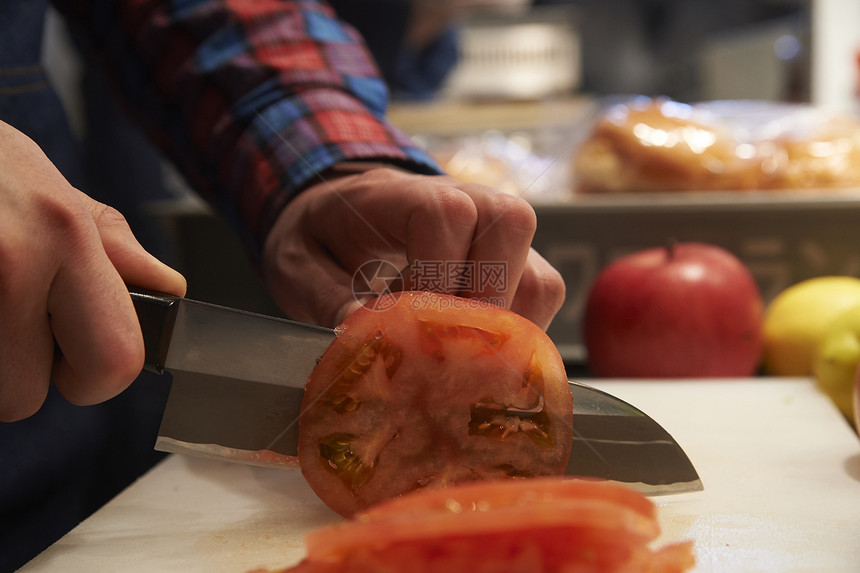 汉堡店厨师为制作汉堡切番茄图片