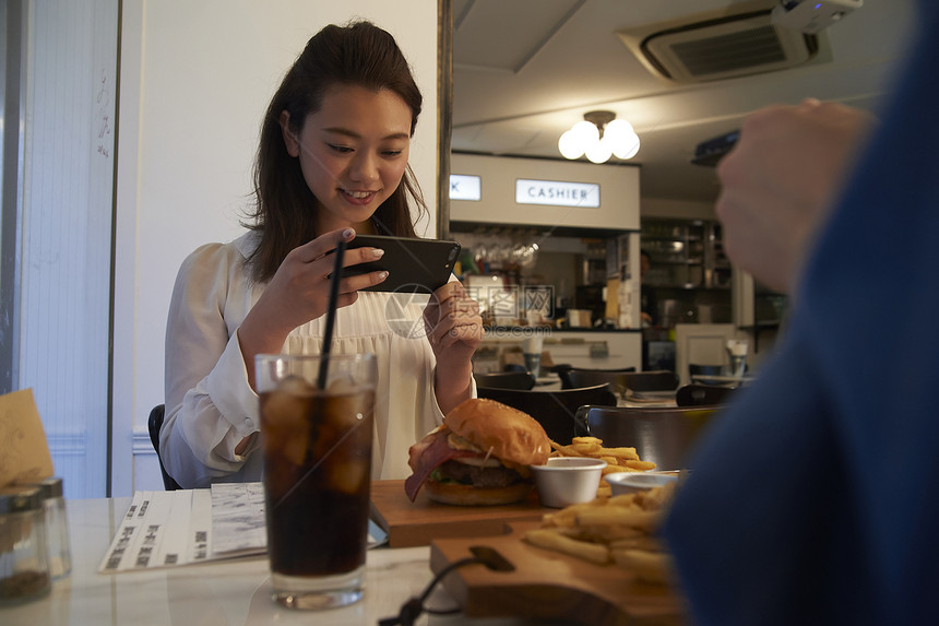 汉堡店内拍摄美食的女生图片