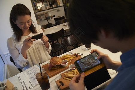 汉堡店内拍摄美食的情侣背景图片