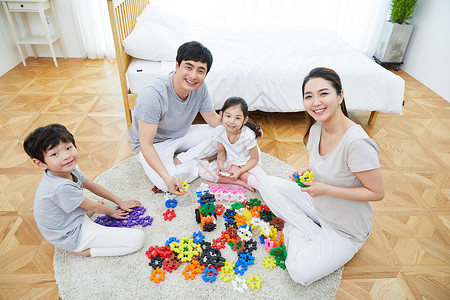 坐在地毯上玩积木的一家人图片