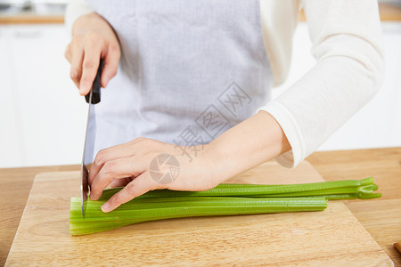 在开放厨房里切菜的年轻女性手部特写背景图片