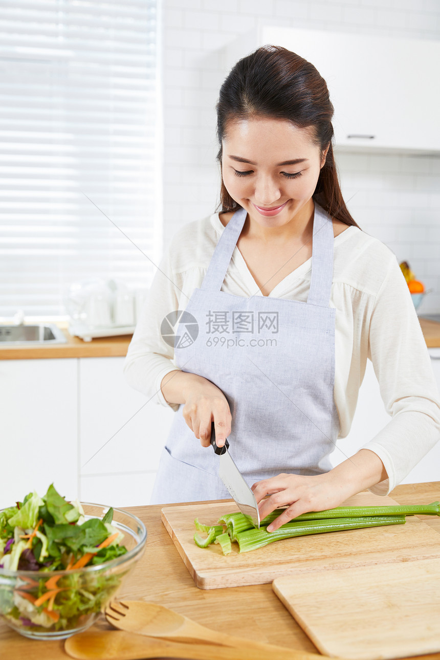 在开放厨房里切菜的年轻女性图片