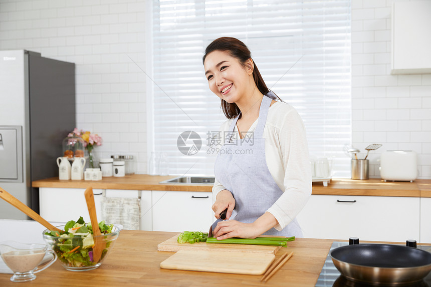 在开放厨房里切菜的年轻女性图片