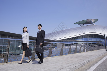 商务都市男女走在机场天桥上图片
