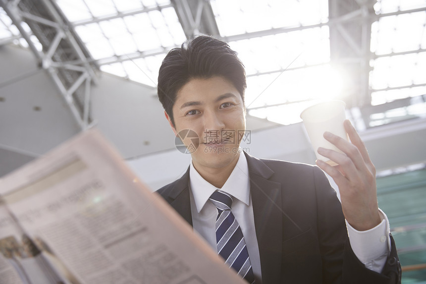  看报纸拿着水杯的商务人士图片