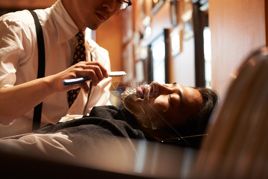 发廊理发师为男人提供理发剃须等服务图片