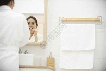 对着镜子洗漱的年轻女性图片