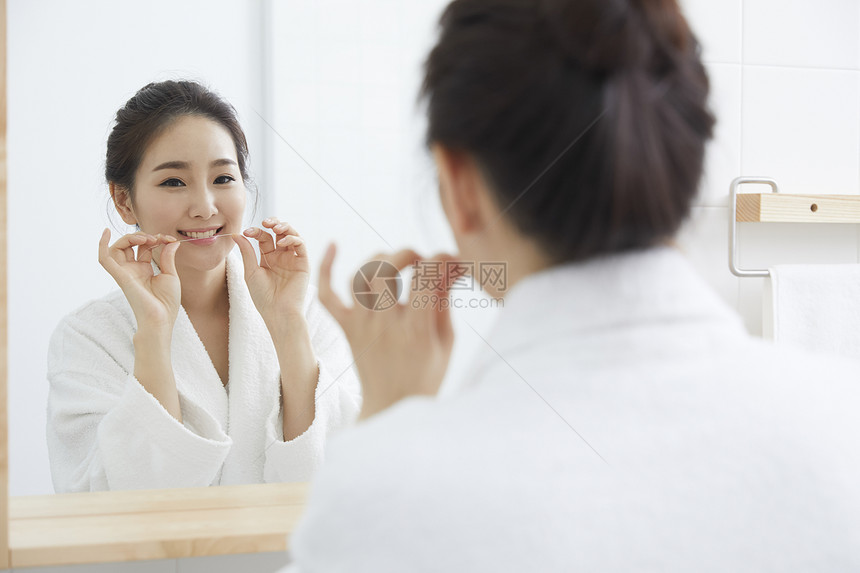 穿着浴袍镜子前洗漱的年轻女性图片