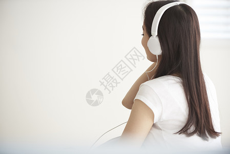 戴着耳机听音乐放松的年轻女性背影图片