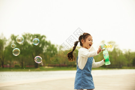 公园里拿着泡泡机玩耍的小女孩图片