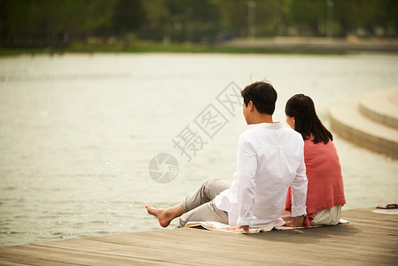 坐在河岸边的夫妇背影图片