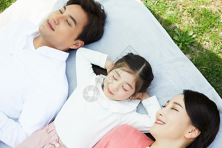 躺在野餐垫上闭眼休息的一家人图片