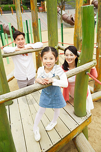 公园游乐场陪伴女儿玩耍的夫妇图片