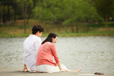 坐在湖边的女孩儿坐在公园湖边嬉戏的夫妻背景