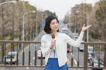 桥上拿着话筒介绍的女记者图片