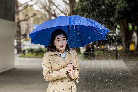 下雨天撑着雨伞播报的年轻女性图片