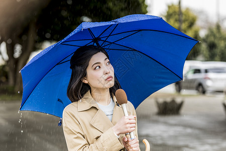 下雨的街道播报新闻的年轻女记者图片